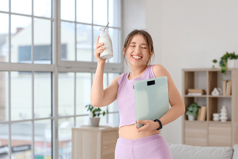 女性_ヨーグルト_持つ_体重計